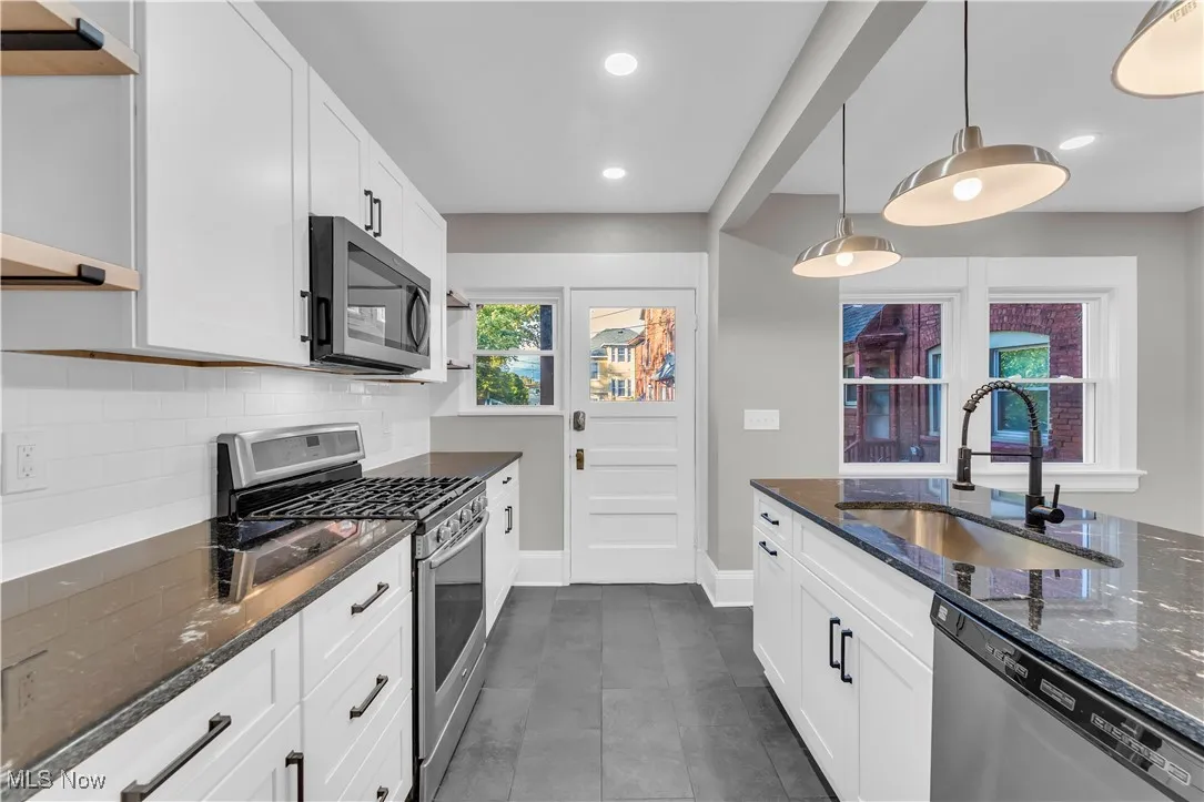 Kitchen with open shelves, dark stone countertops, stainless steel appliances, white cabinets, and recessed lighting