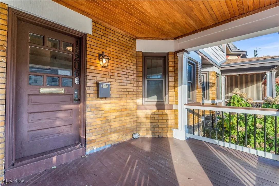 Doorway to property featuring brick siding and a porch