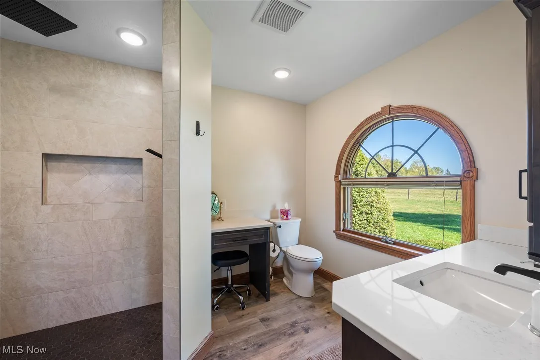 Bathroom featuring vanity, walk in shower, light wood-style flooring, and recessed lighting