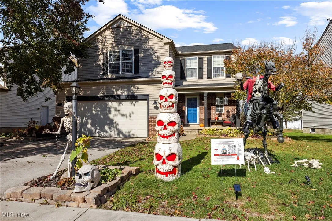 Traditional-style home with a porch, driveway, a garage, and a front yard