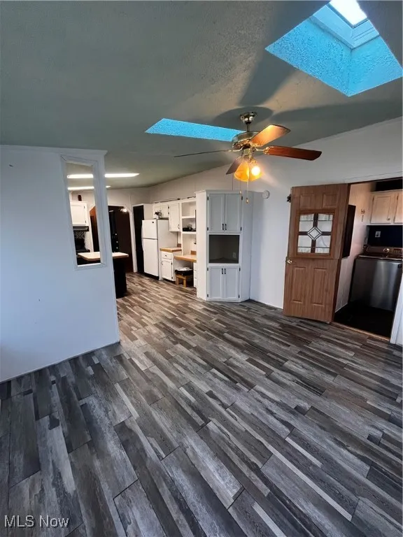 Unfurnished living room with a skylight, dark wood finished floors, a textured ceiling, and a ceiling fan