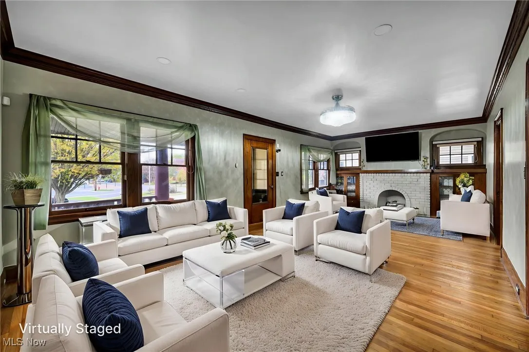 Living room with crown molding, a brick fireplace, and wood finished floors