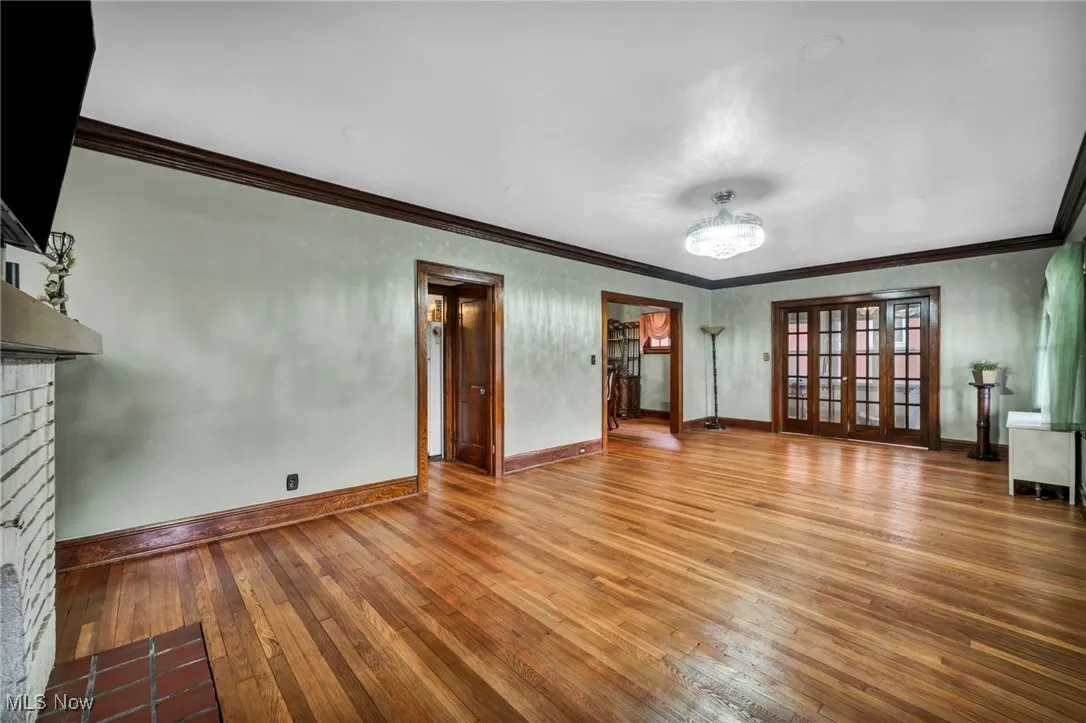 Unfurnished living room featuring a fireplace, wood-type flooring, and ornamental molding
