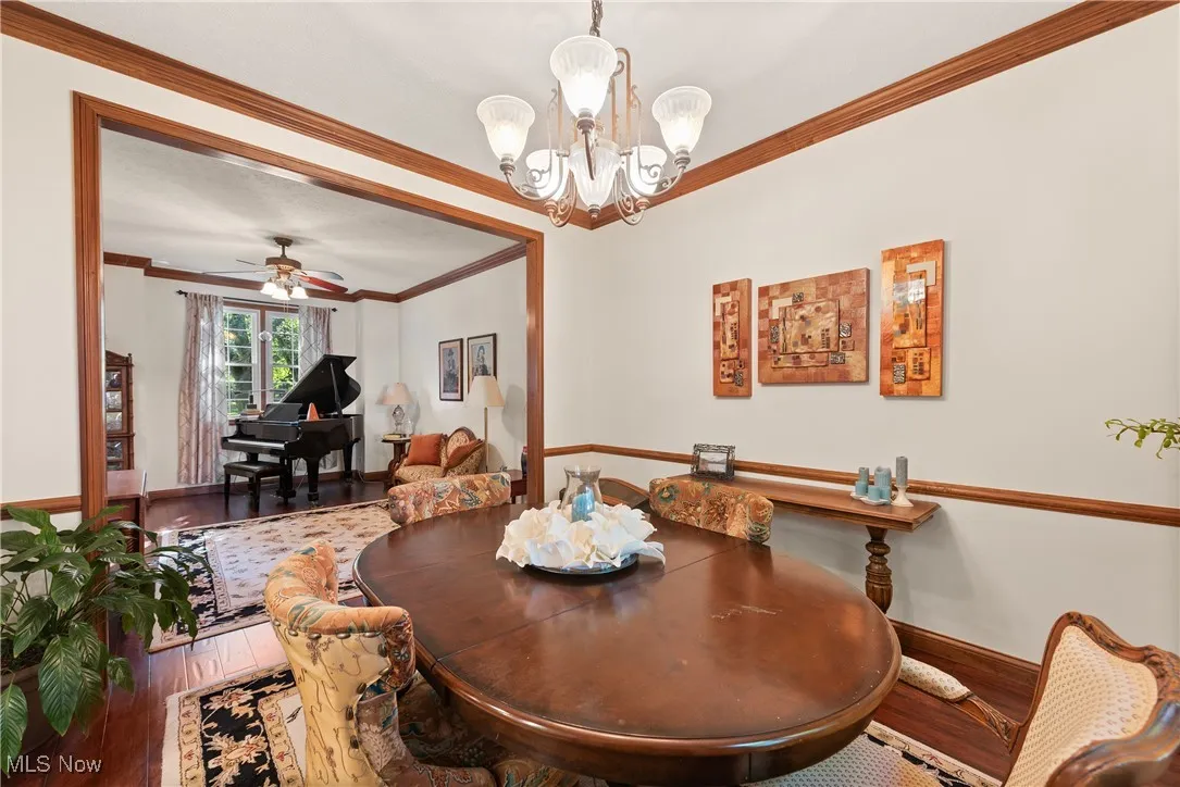 Dining space with crown molding, hardwood / wood-style flooring, a ceiling fan, and a chandelier