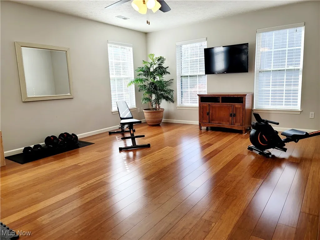 Workout area with a textured ceiling, hardwood / wood-style floors, and ceiling fan
