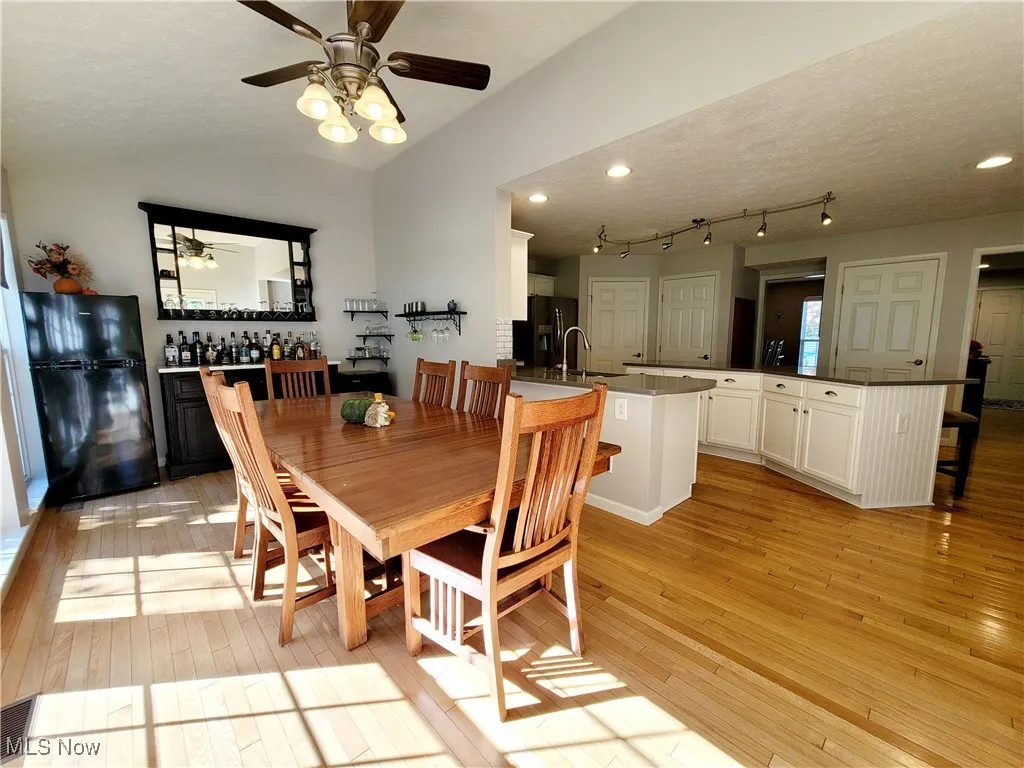 Dining space featuring a textured ceiling, light wood-style floors, ceiling fan, and vaulted ceiling