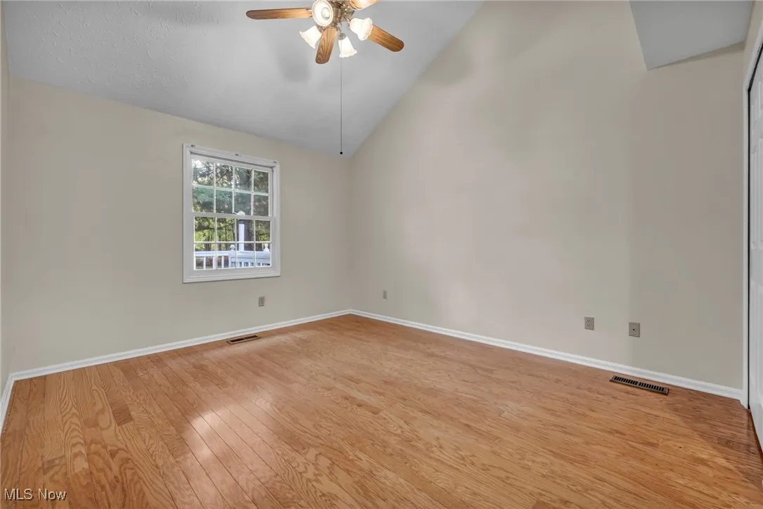 Spare room featuring light wood-style floors, vaulted ceiling, ceiling fan, and a textured ceiling