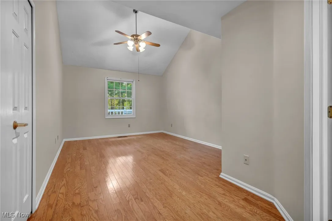 Unfurnished room with vaulted ceiling, light wood finished floors, and a ceiling fan