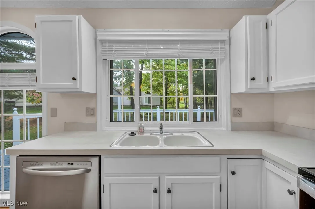 Kitchen featuring white cabinetry, stainless steel dishwasher, and light countertops
