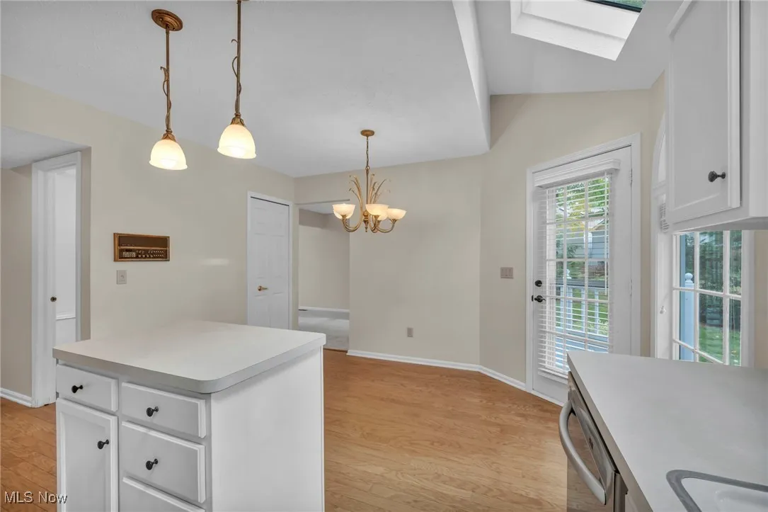 Kitchen featuring white cabinets, pendant lighting, light wood-style flooring, and light countertops