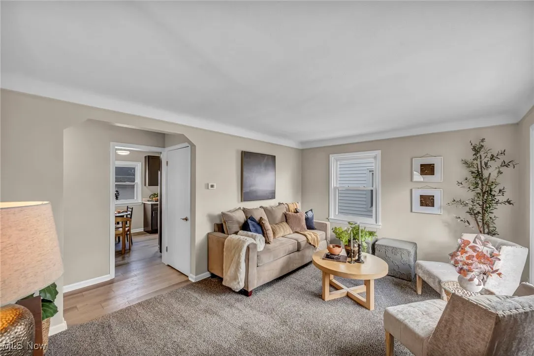 Living room with arched walkways, light colored carpet, and light wood-type flooring