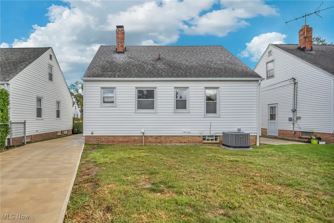 Back of property with a patio area, a lawn, roof with shingles, and a chimney