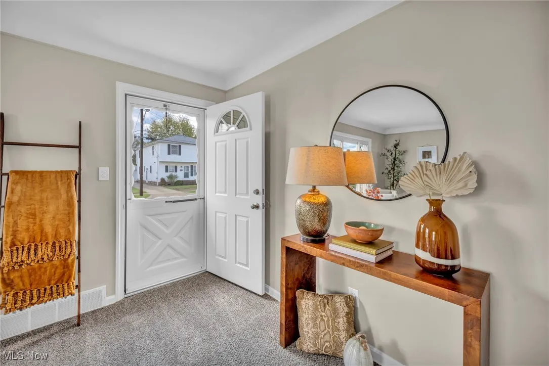 Doorway with carpet floors and baseboards