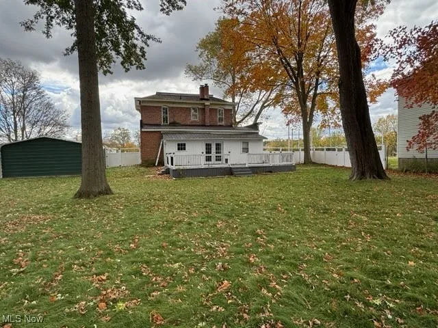 Back of property with a deck, a chimney, and a fenced backyard