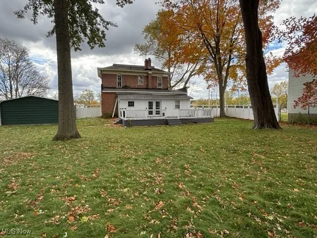 Rear view of property featuring a wooden deck, a chimney, and a fenced backyard