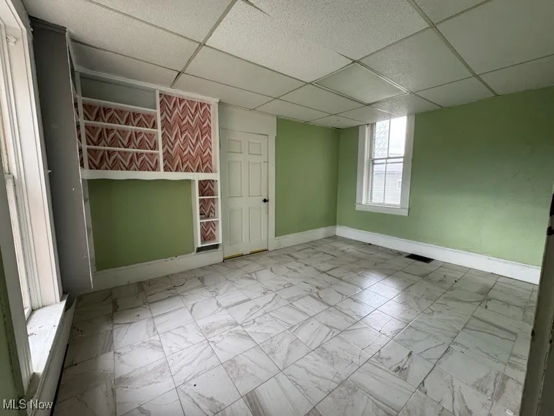 Spare room with a drop ceiling and light marble finish flooring