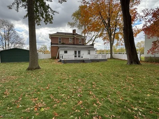 Back of house featuring a deck, a fenced backyard, and a chimney
