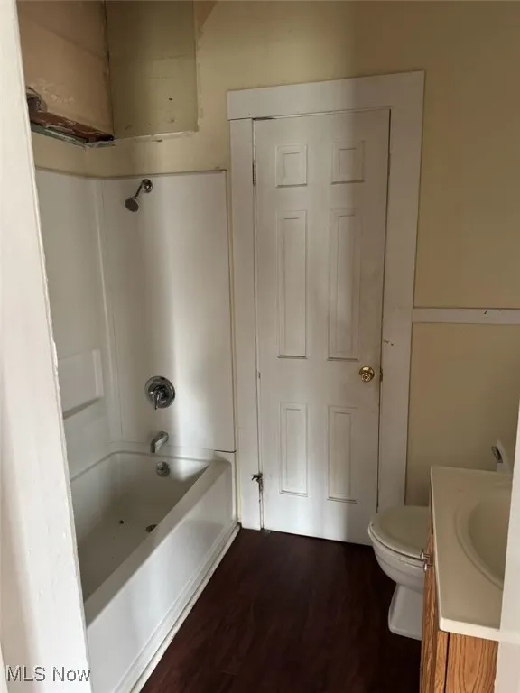 Bathroom featuring vanity, dark wood-style flooring, and  shower combination