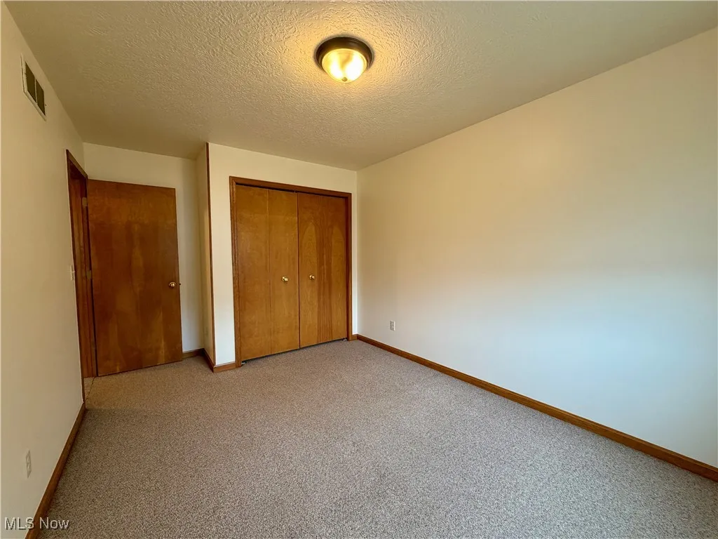 Unfurnished bedroom featuring a textured ceiling, a closet, and carpet flooring