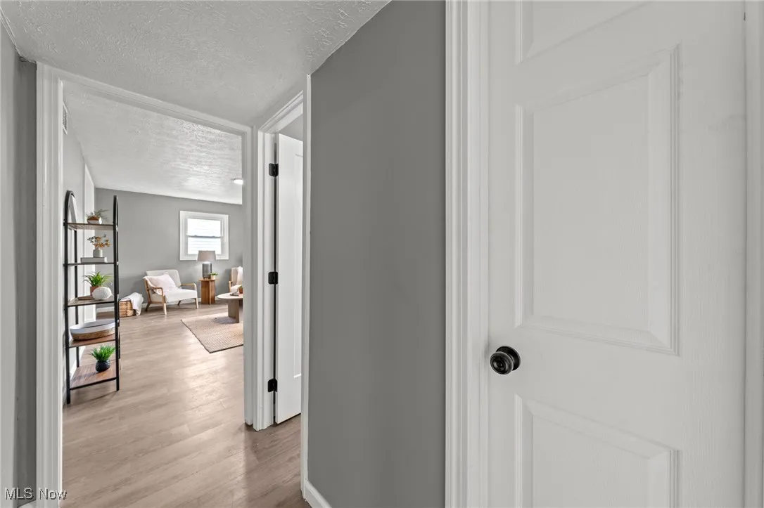 Hallway featuring a textured ceiling and light wood-style flooring