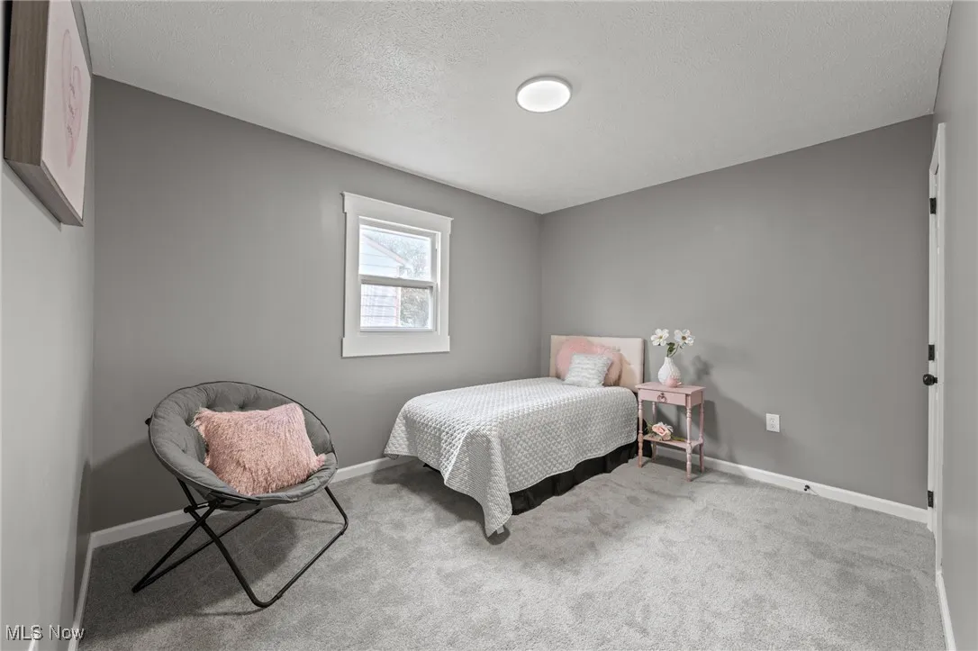 Carpeted bedroom with a textured ceiling and baseboards