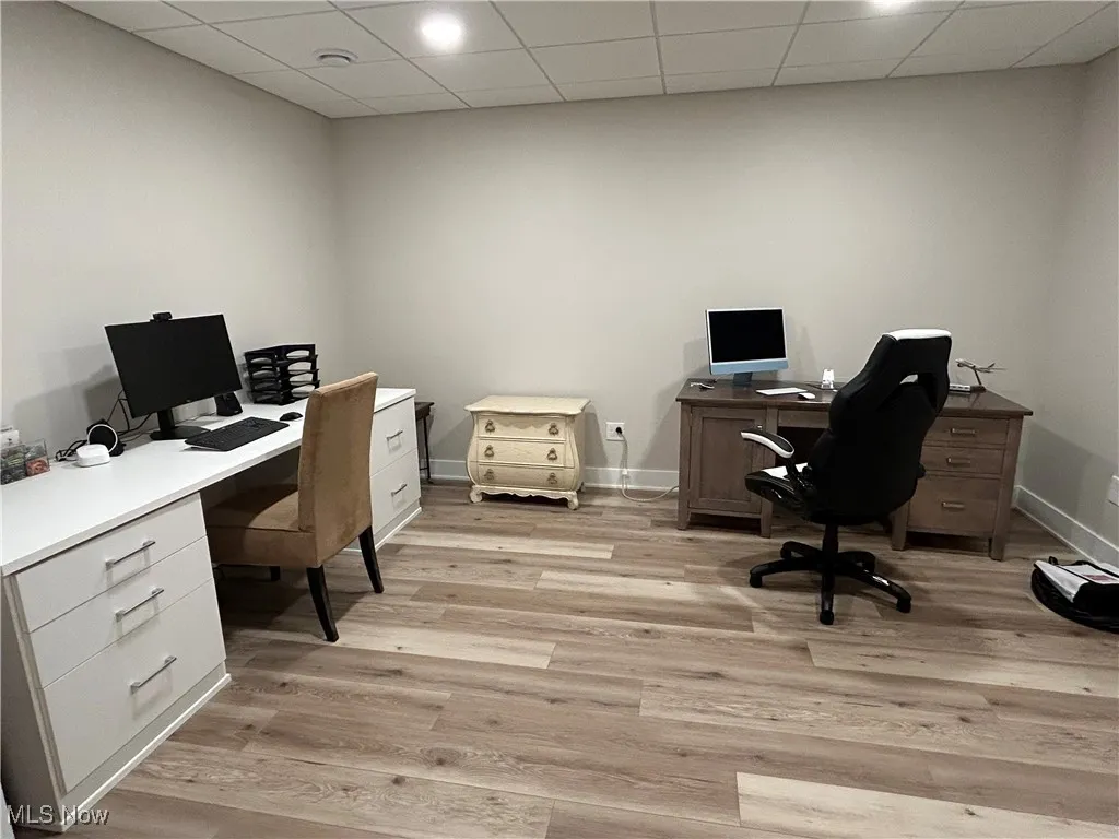 Office space with a paneled ceiling and light wood-style flooring