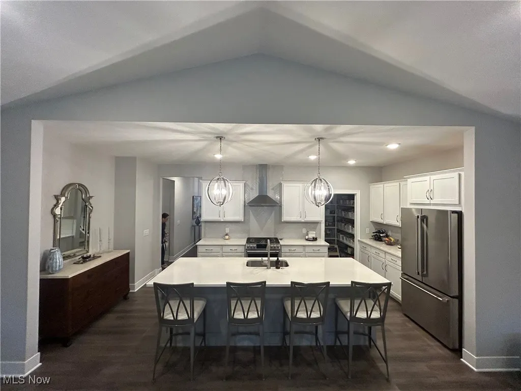 Kitchen featuring high end appliances, white cabinets, a breakfast bar area, recessed lighting, and dark wood finished floors