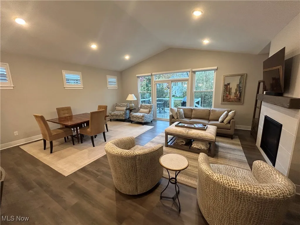 Living room with vaulted ceiling, dark wood-style flooring, recessed lighting, and a tiled fireplace