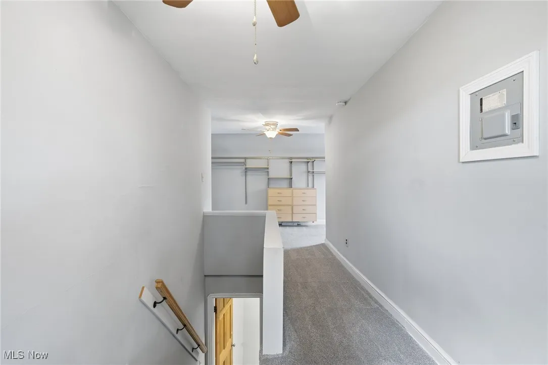 Hallway featuring dark carpet and an upstairs landing