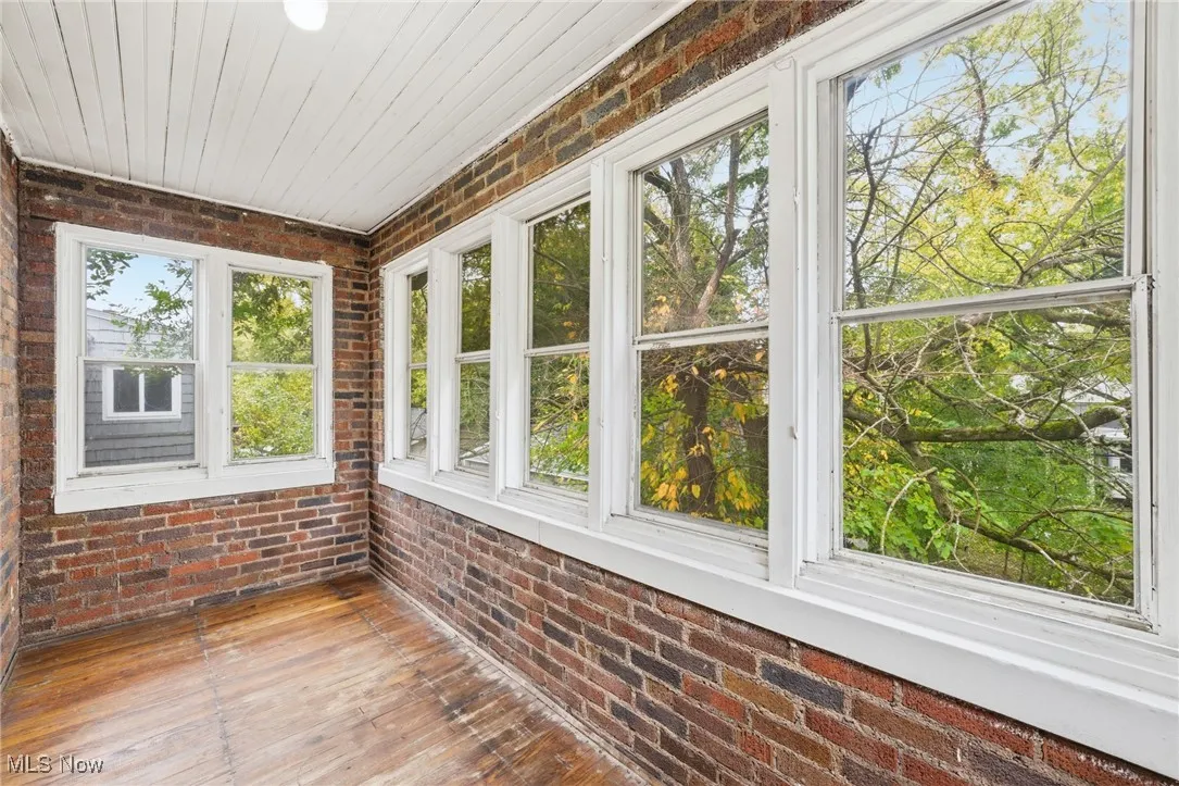Unfurnished sunroom with brick wall and hardwood / wood-style floors