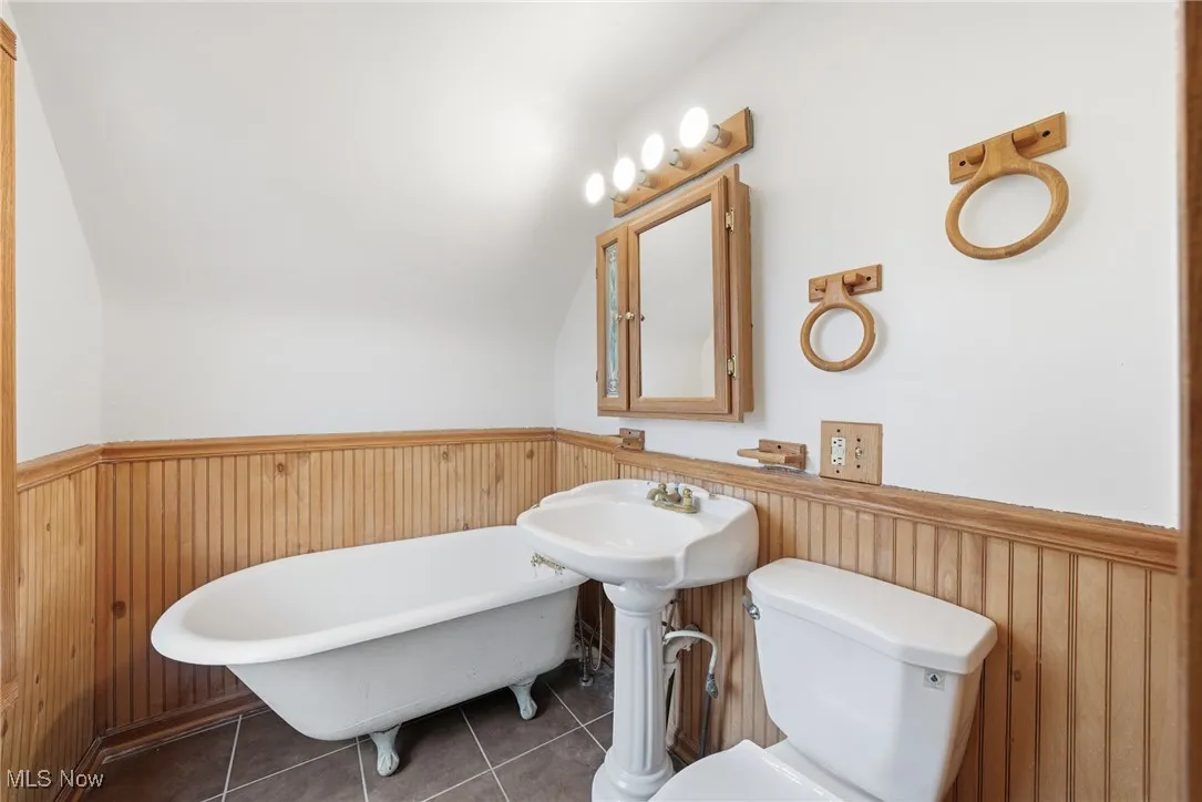 Full bath featuring a freestanding tub, wooden walls, a wainscoted wall, and tile patterned flooring