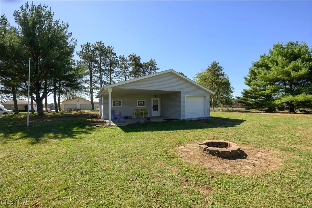 Back of house with a fire pit, a patio area, and a yard