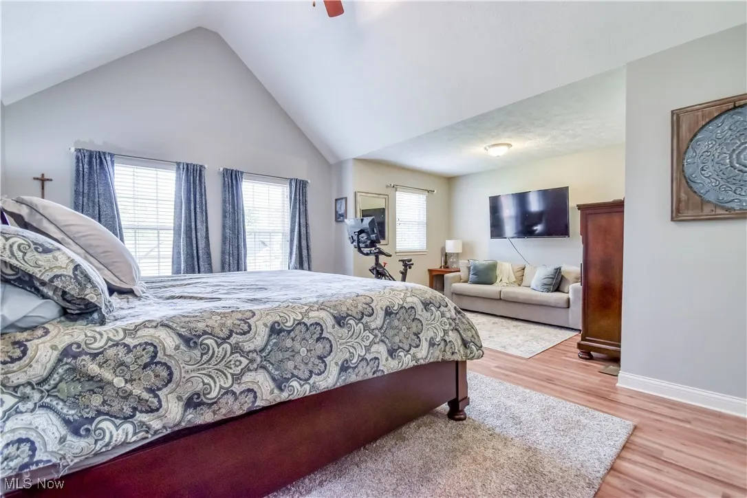 Bedroom with light wood-type flooring, ceiling fan, and vaulted ceiling