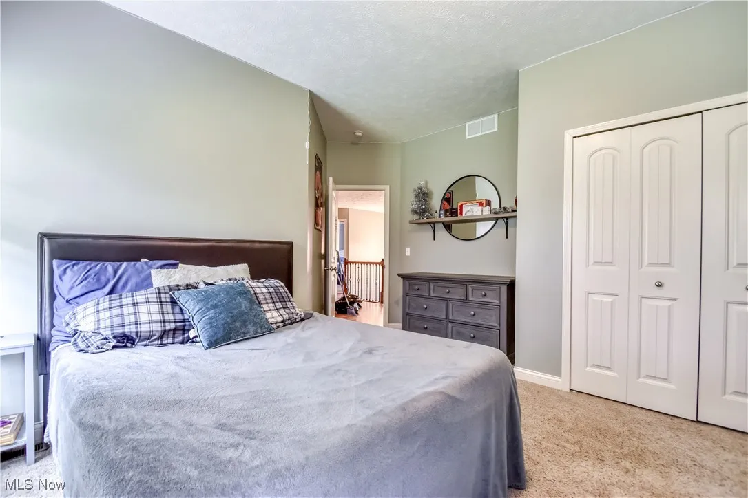 Bedroom with light colored carpet, a closet, and a textured ceiling
