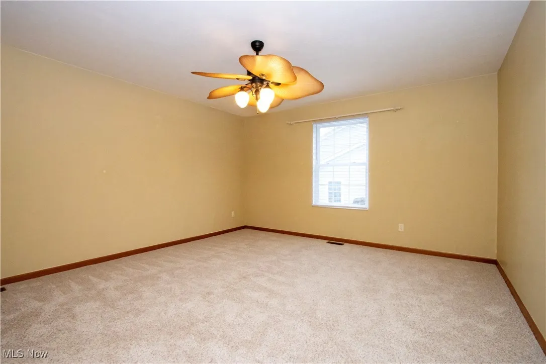 Spare room featuring light colored carpet and ceiling fan