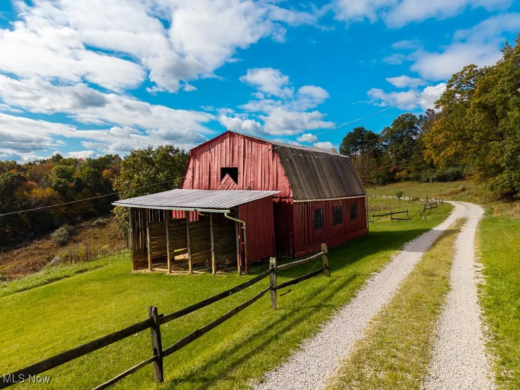 View of barn featuring driveway and a forest view
