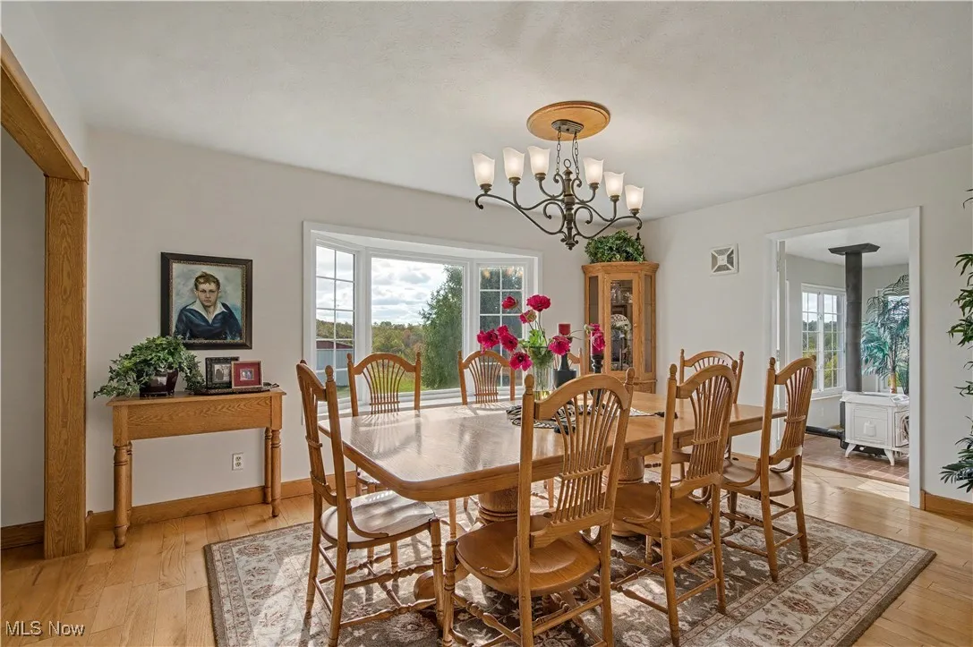Dining room featuring light wood-type flooring, a wood stove, and a chandelier