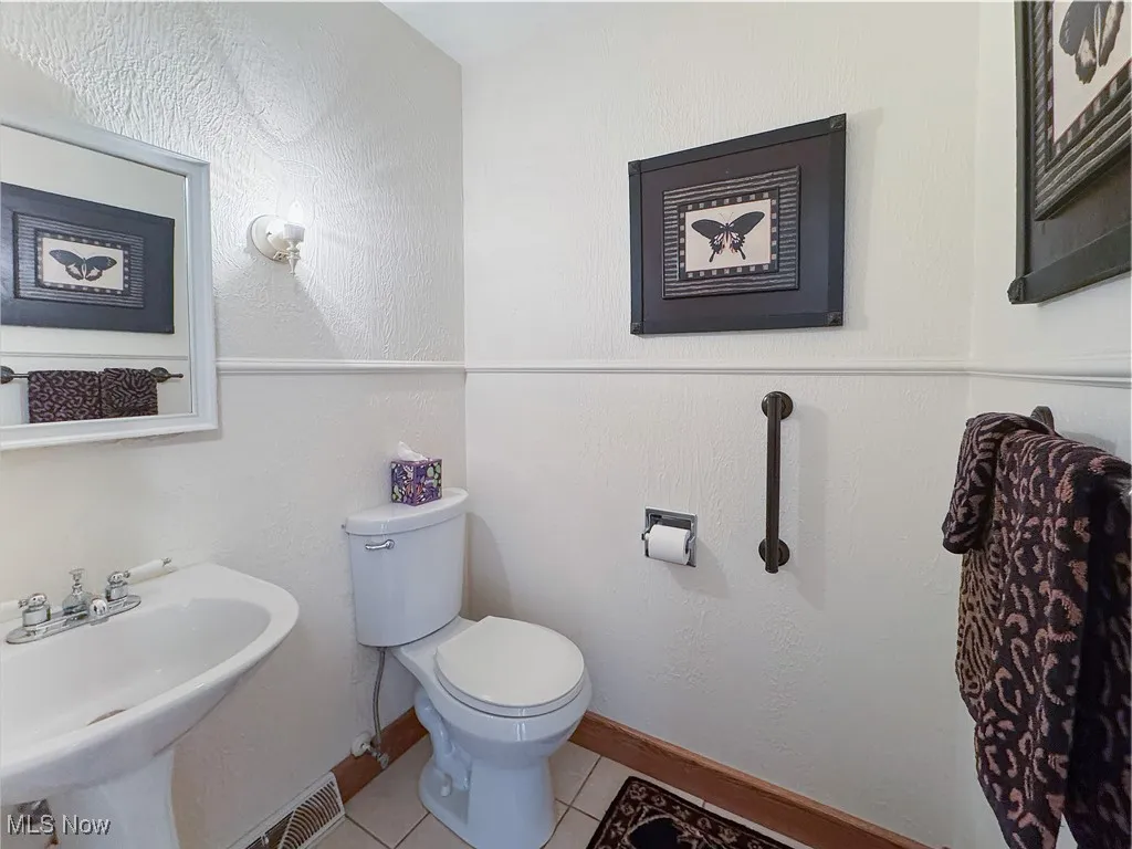 Bathroom with a textured wall and tile patterned flooring