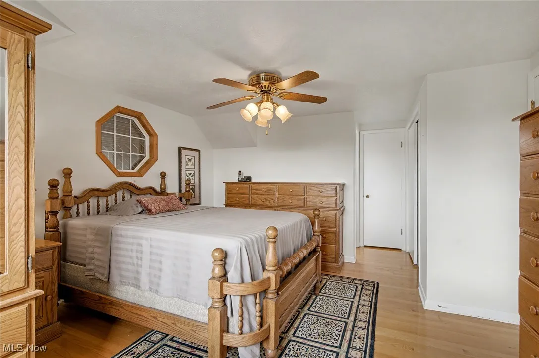 Bedroom with light wood-style floors, a ceiling fan, and vaulted ceiling