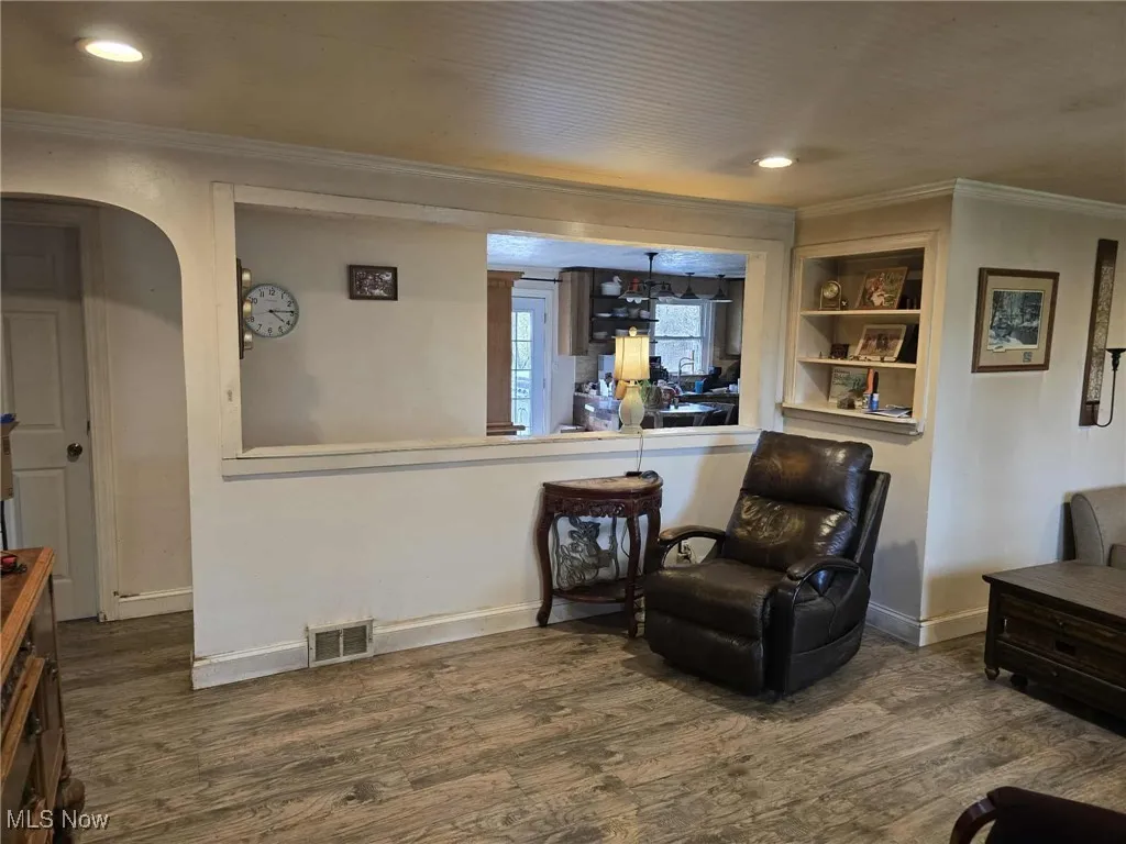 Living area with crown molding, dark wood-style flooring, recessed lighting, and arched walkways