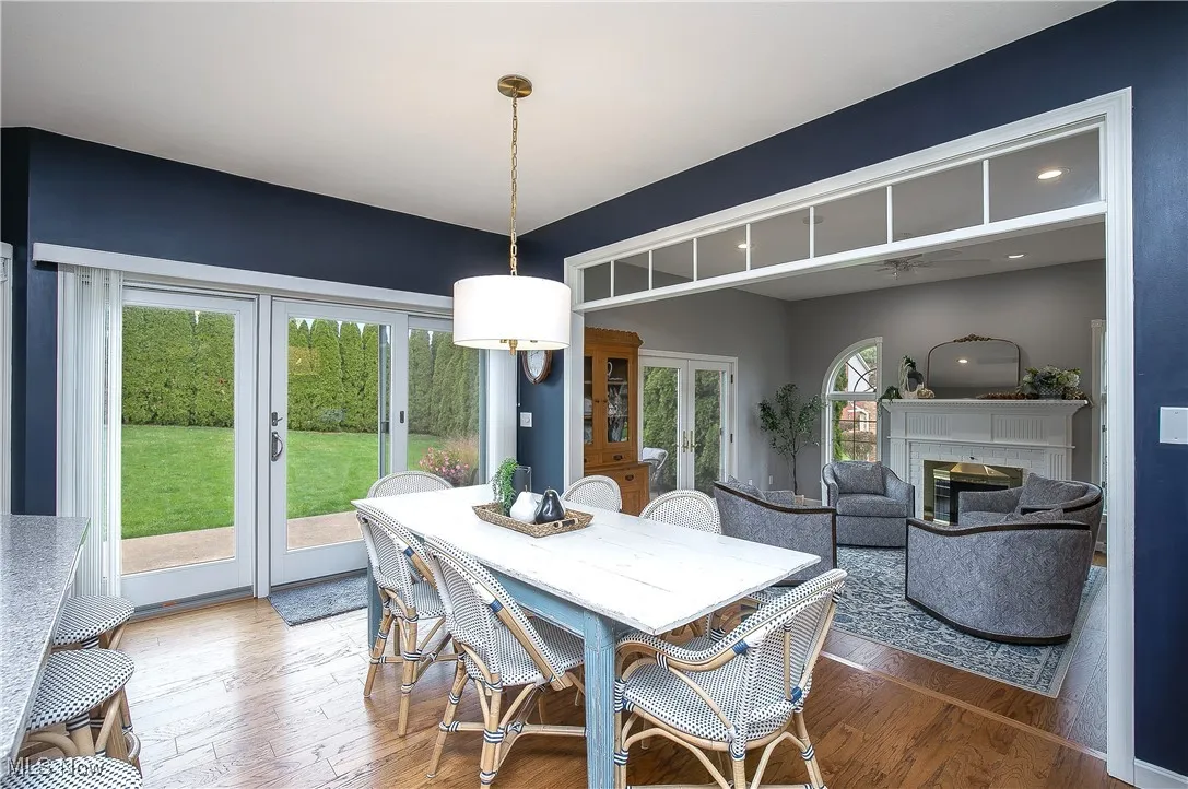 Dining room with french doors, a glass covered fireplace, wood finished floors, and a ceiling fan