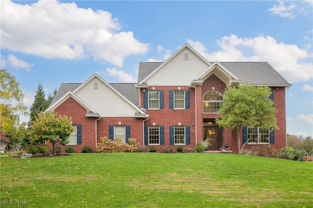 Colonial inspired home featuring a front lawn, brick siding, and a shingled roof