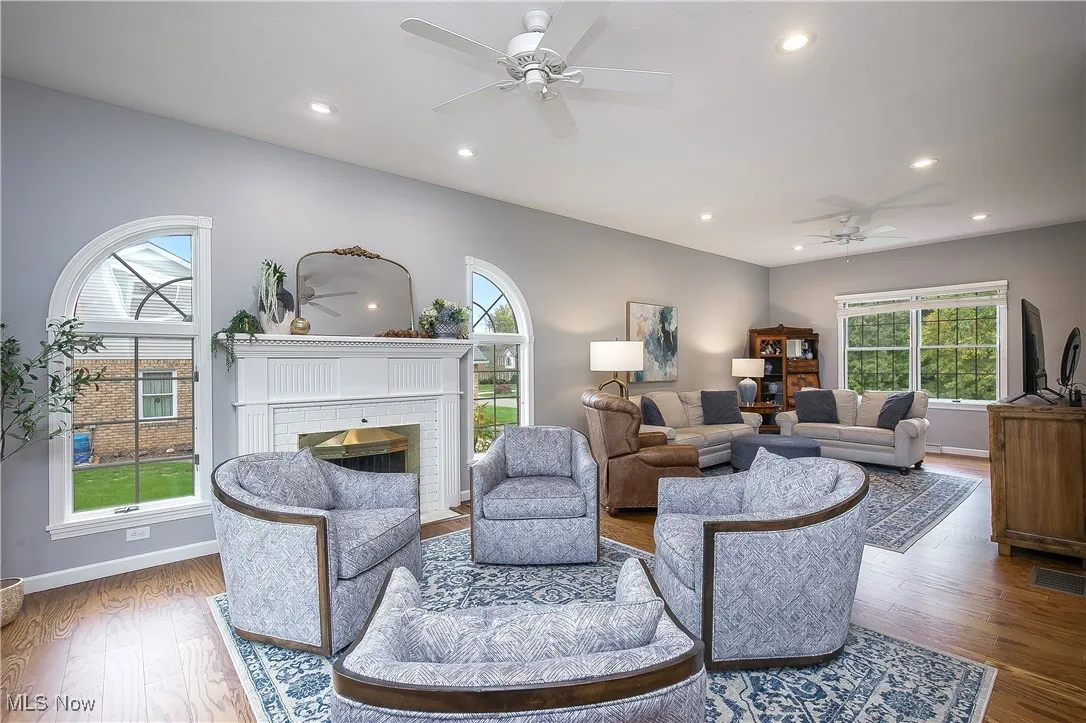 Living room with ceiling fan, a brick fireplace, recessed lighting, and wood finished floors