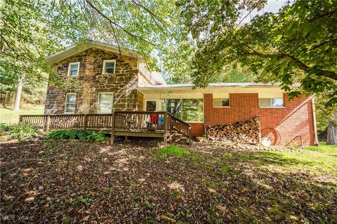 Front of property featuring stone construction and a deck