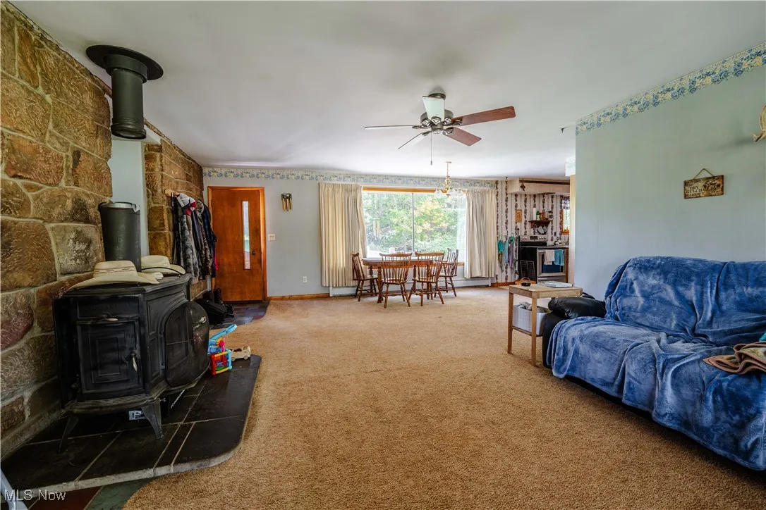 Carpeted living room with a wood stove and a ceiling fan