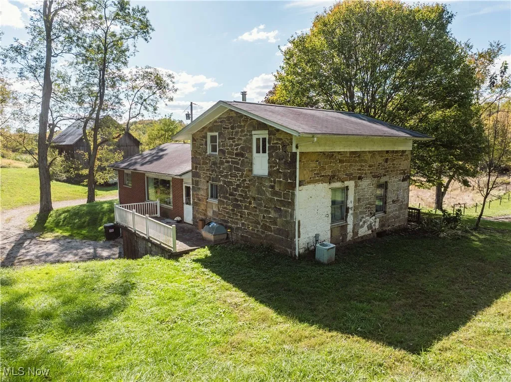 View of side of property with stone siding, a yard, and covered porch