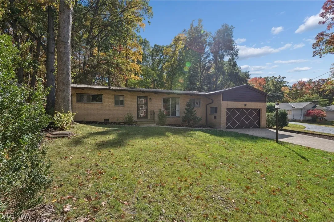 Ranch-style house featuring concrete driveway, a front lawn, brick siding, and an attached garage