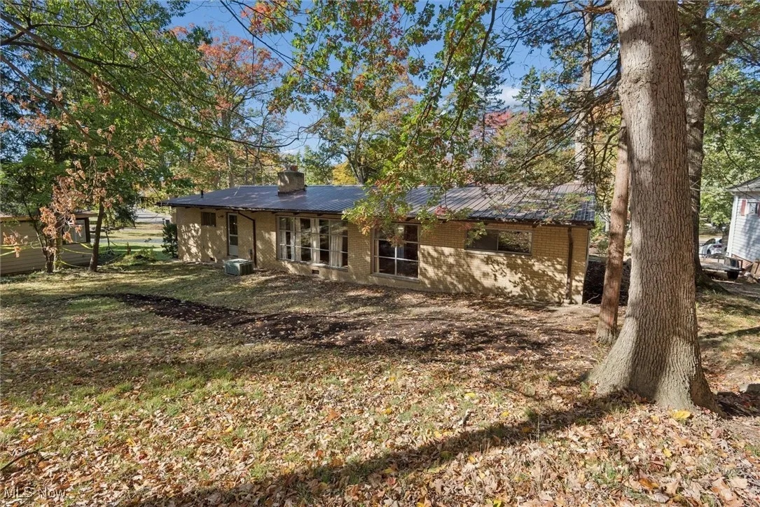 Back of property featuring brick siding, a chimney, and a yard