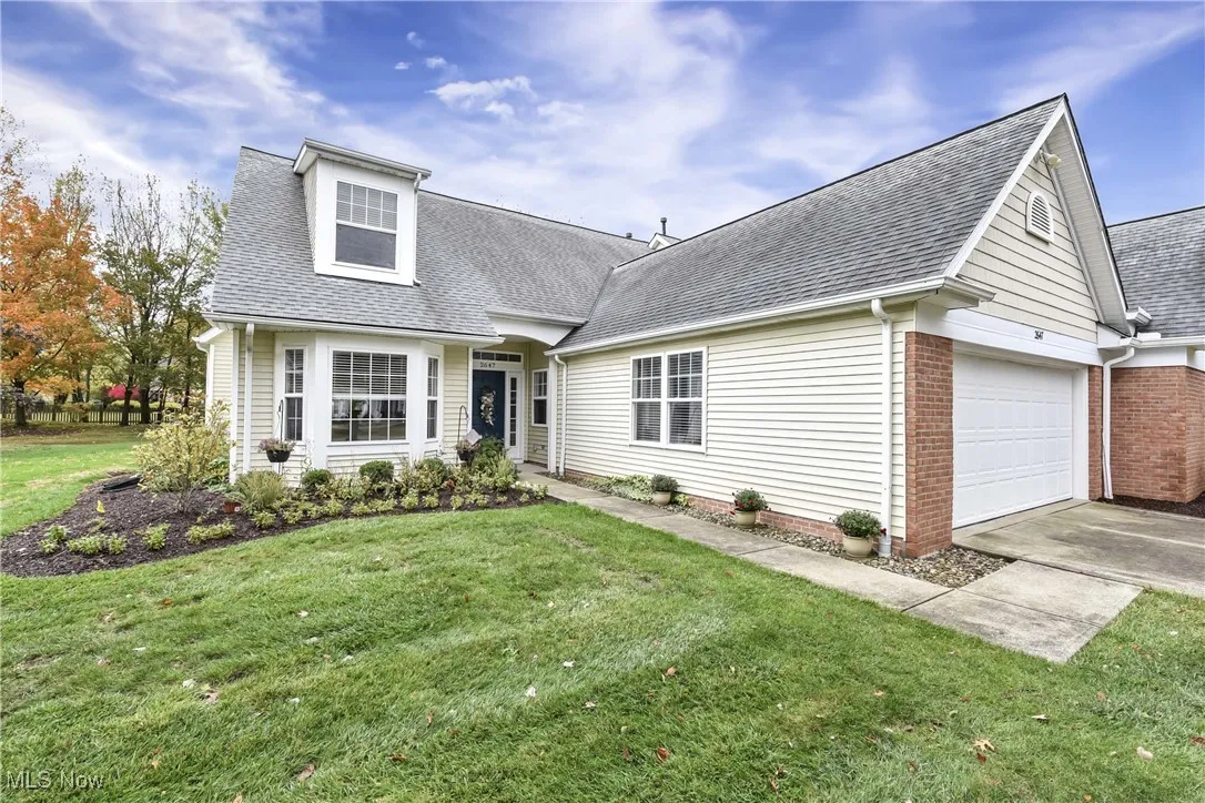 View of front of property featuring a shingled roof, a front lawn, driveway, and an attached garage