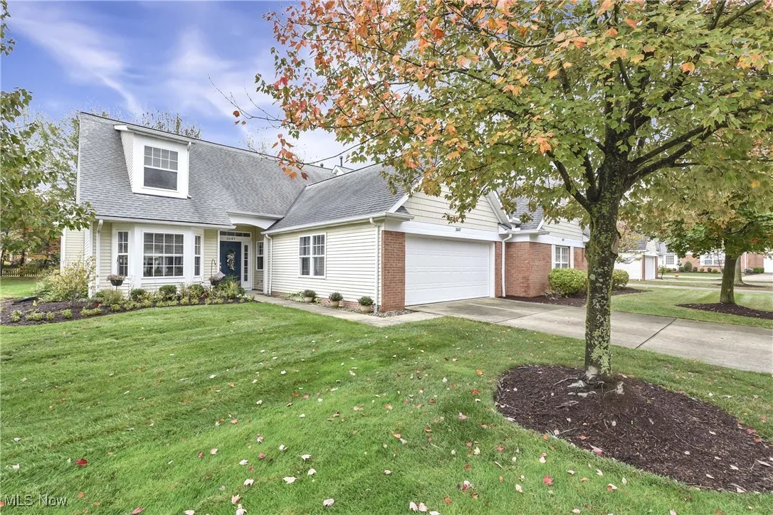 View of front of home featuring driveway, a front yard, brick siding, and roof with shingles